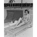 Beauty young woman sitting on lounge chair looking at camera and smiling Poster Print (24 x 36)