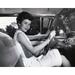 Young woman sitting in the driver s seat of a car and smiling Poster Print (24 x 36)