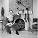 Portrait of Santa Claus Sitting in Front of a Fireplace & Holding a Christmas Present Poster Print - 18 x 24 in.