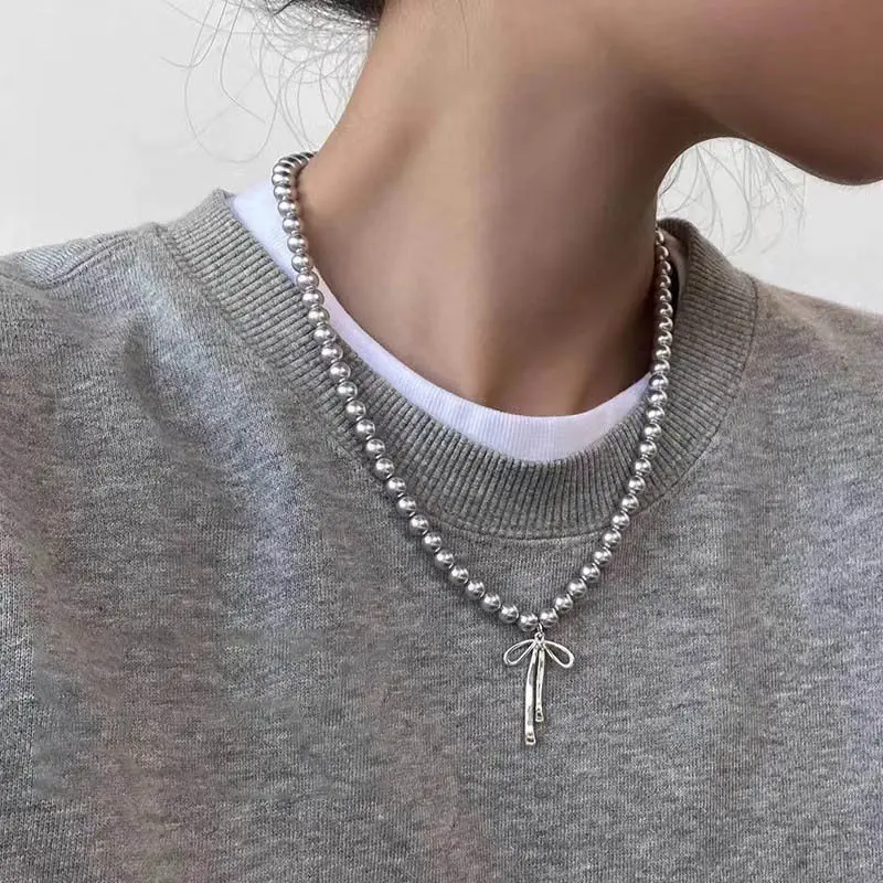 Modischer Halsreif mit Anhänger. Anmutige Halsband-Halskette mit Schleife und grauen Perlen. Halsschmuck-Accessoires Image