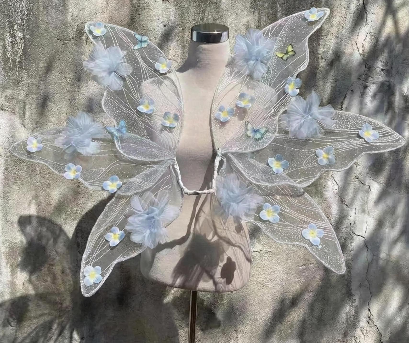 Ali di fata a forma di farfalla con fiori blu, accessorio per costume cosplay a tema bosco.