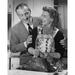 Mid adult man woman preparing a turkey and a mid adult man holding her from behind Poster Print (24 x 36)